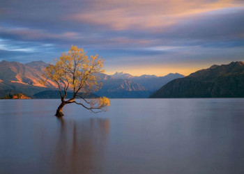 Een fotobehang van een magische zonsondergang bij een bergmeer.