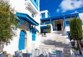 Fotobehang van een straat in Tunesië, met blauwe huizen en een mediterrane sfeer.