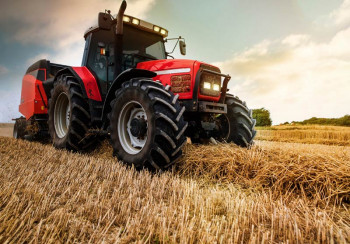 Fotobehang tractor op het land; een krachtige tractor maakt strobalen op een akker.