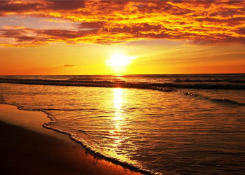 Fotobehang van een zonsondergang aan het strand boven zee.