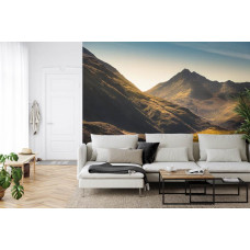 Een fotobehang met een panoramisch berglandschap in warme ochtendkleuren, perfect voor een woonkamer.