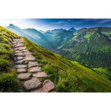 Fotobehang van een bergpad dat langs de bergtoppen slingert, met een weids uitzicht over het landschap.