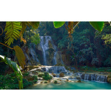 Fotobehang van de betoverende Kuang Si-waterval in Laos, waar het water door een dicht boslandschap stroomt.