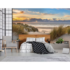 Fotobehang met de duinen bij de Noordzee met een uitgestrekt strand en een schitterende zonsondergang, met warme kleuren in een stijlvolle slaapkamer.