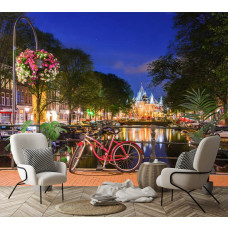 Fotobehang rode fiets op Amsterdamse brug in een woonkamer, met warme verlichting en avondbeeld van de stad op de muur.