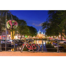 Fotobehang met rode fiets op een Amsterdams bruggetje bij avond, omringd door verlichte grachtenpanden en stille grachten.