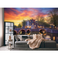 Een woonkamer met een fotobehang met oude herenhuizen op de hoek van de Keizersgracht en Leidsegracht in Amsterdam, met verlichte bruggetjes die de avond verlichten.