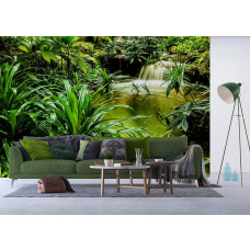 Een huiskamer met een fotobehang van een waterval tussen tropische groene planten in een jungle.