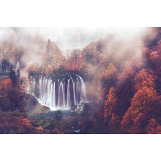 Fotobehang van een waterval die door een mistig herfstbos stroomt, omringd door bergen en bomen.