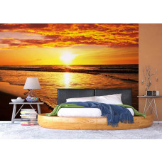 Fotobehang van een zonsondergang aan het strand boven zee, gepresenteerd in een slaapkamer.