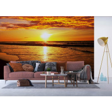 Een woonkamer met een fotobehang van een zonsondergang aan het strand boven zee.