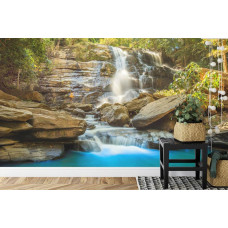 Een prachtig fotobehang van een zonnige waterval met rotsen en natuurlijke elementen, ideaal voor een slaapkamer.